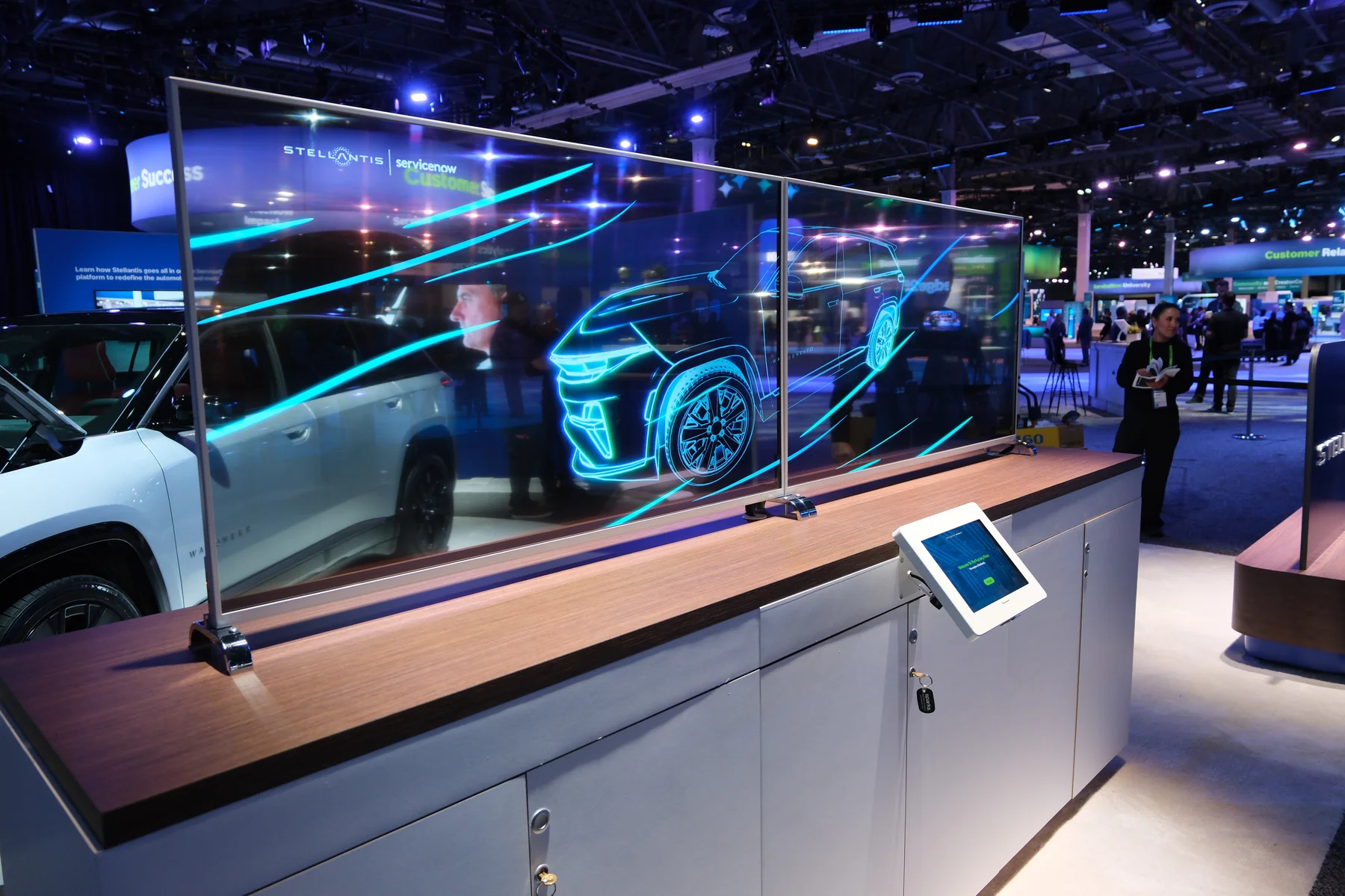 A panoramic transparent display shows a glowing automotive visualization in the exhibition.